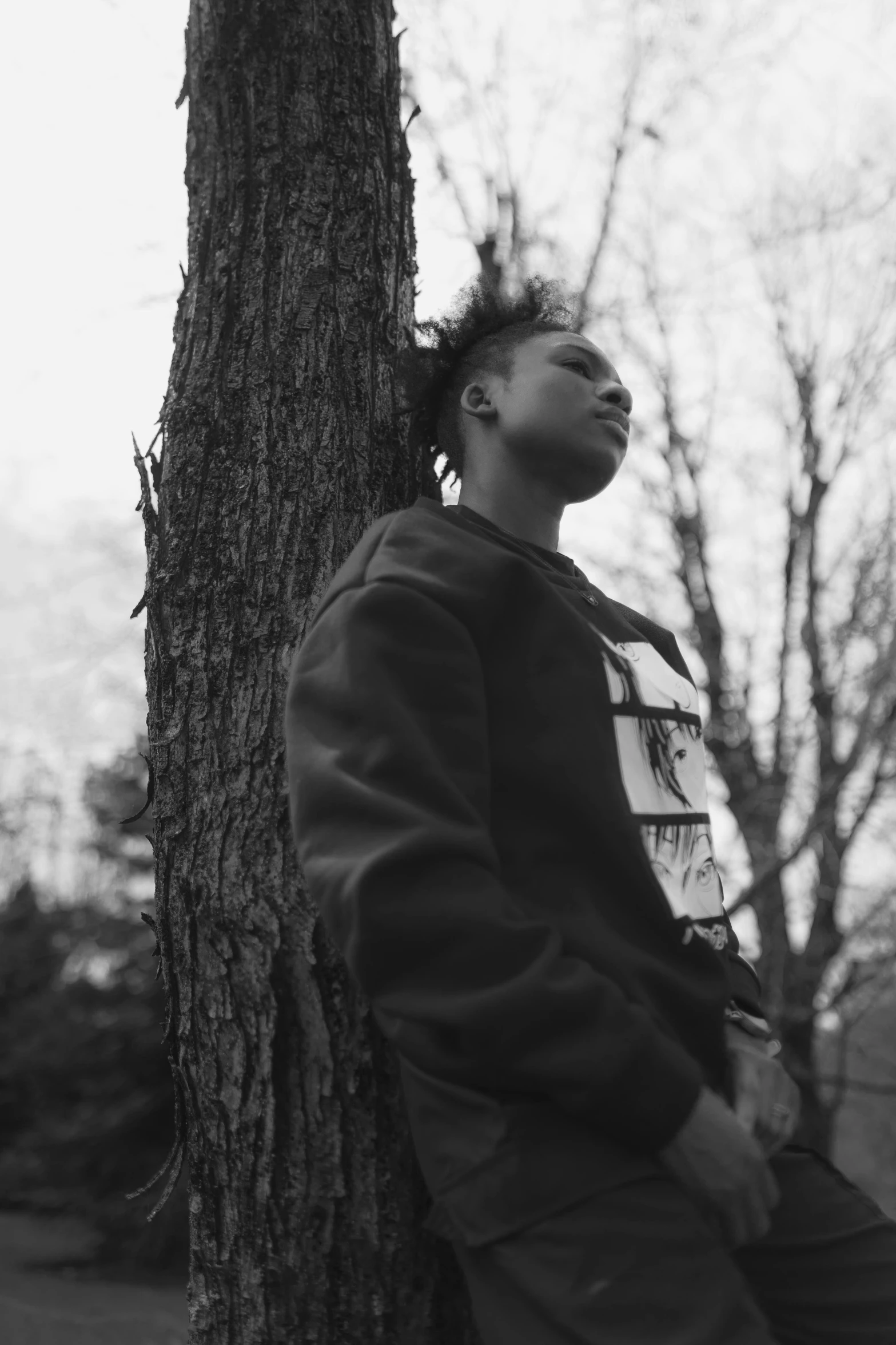 a man sitting in the middle of a tree next to a street