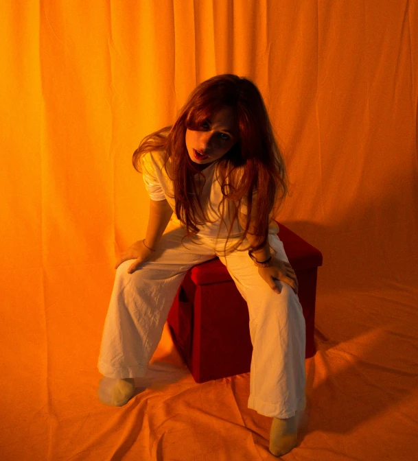 woman wearing white pants sitting on the back of a red bench