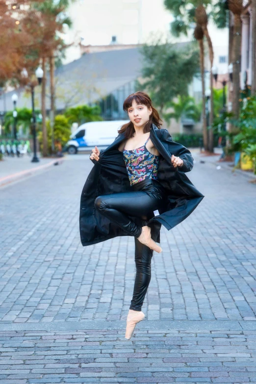 a girl in black coat and leggings on brick street