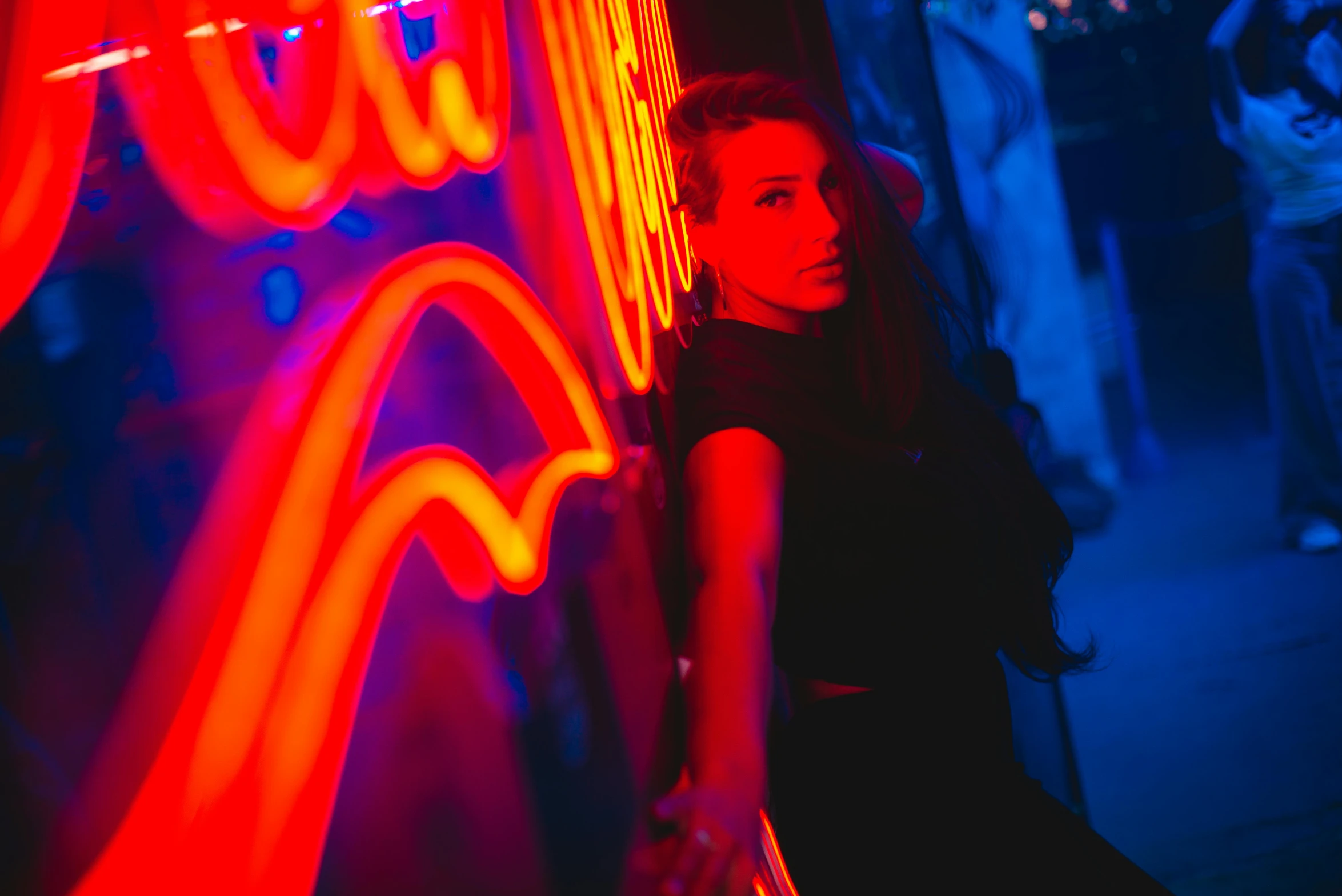 the woman is posing in front of an illuminated neon sign