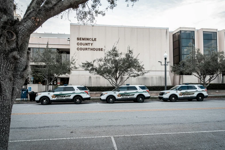 three police cars parked outside of a courthouse