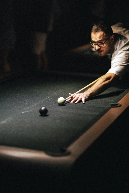 a man taking a ball to put in a pool table