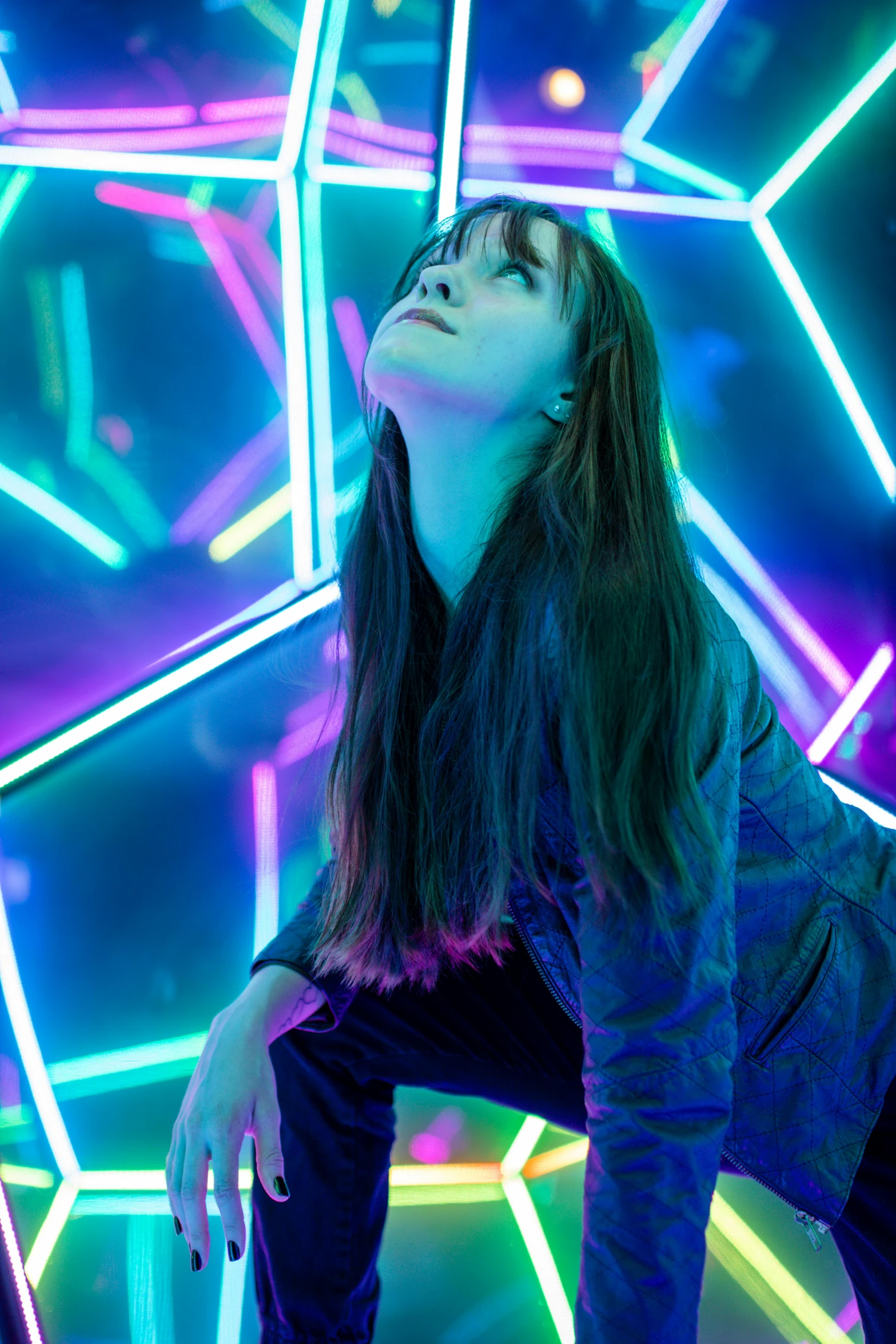 an attractive woman is kneeling in front of neon lights