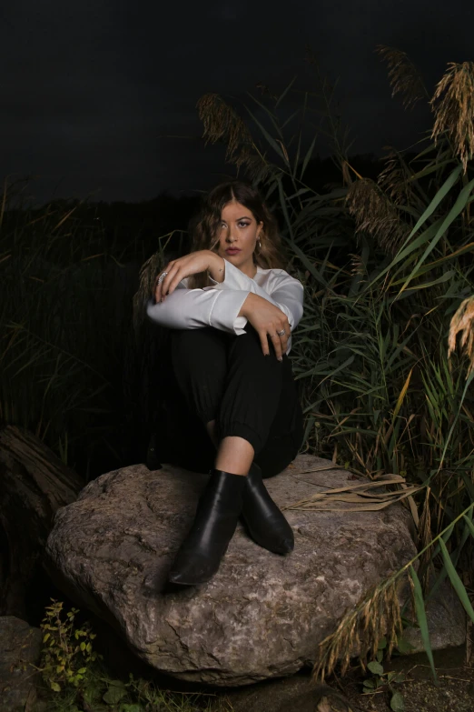 woman sitting on rock outdoors at night with plants