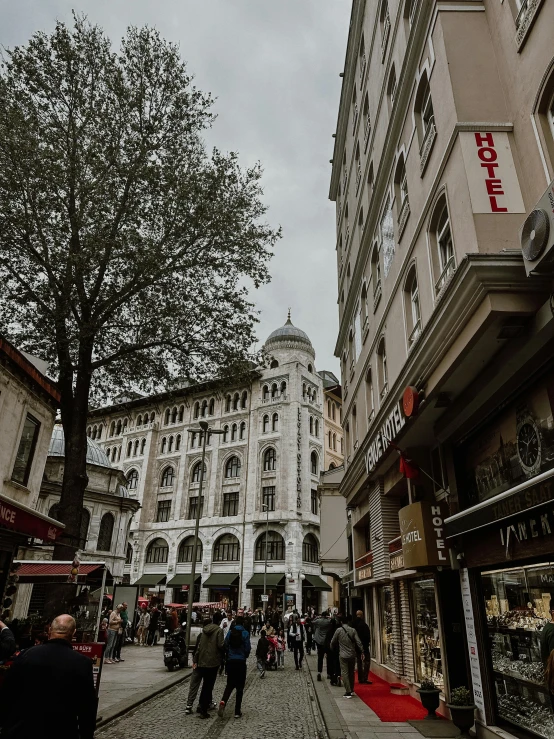 several people walking on a city street in front of tall buildings