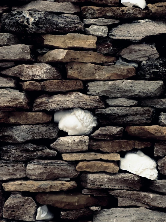 some snow is sticking out of the stone wall