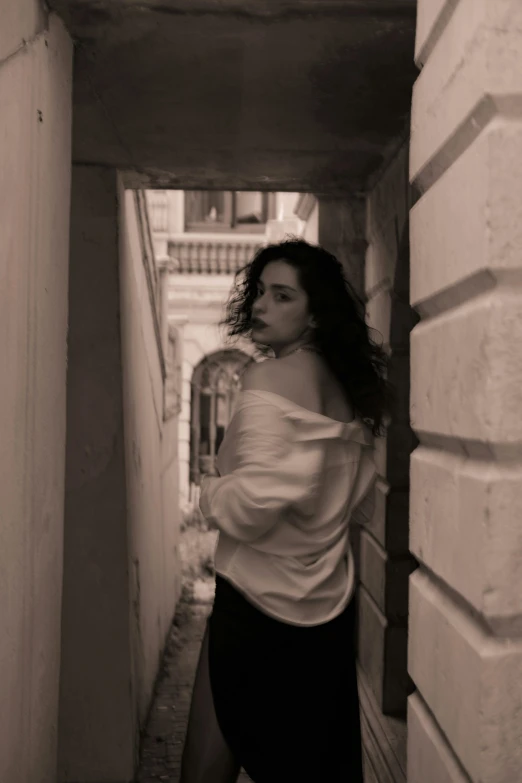 black and white pograph of woman standing in between a wall