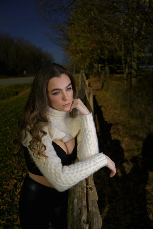 a woman leaning on a fence in front of a field