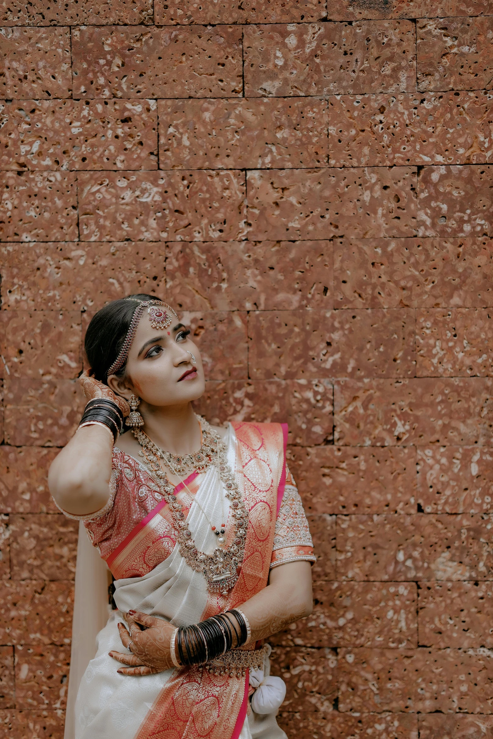 a woman in a white sari standing next to a brick wall