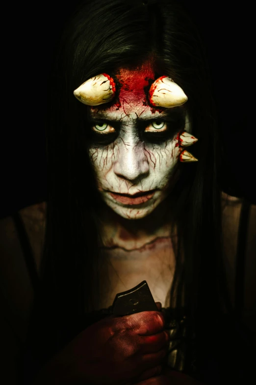 a woman with  and demon makeup holds a phone