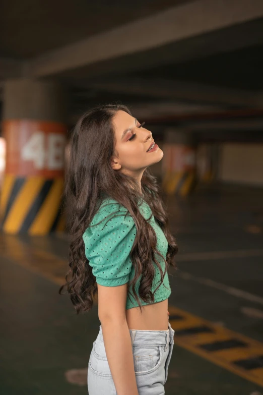 the woman in the green top is standing near a parking lot