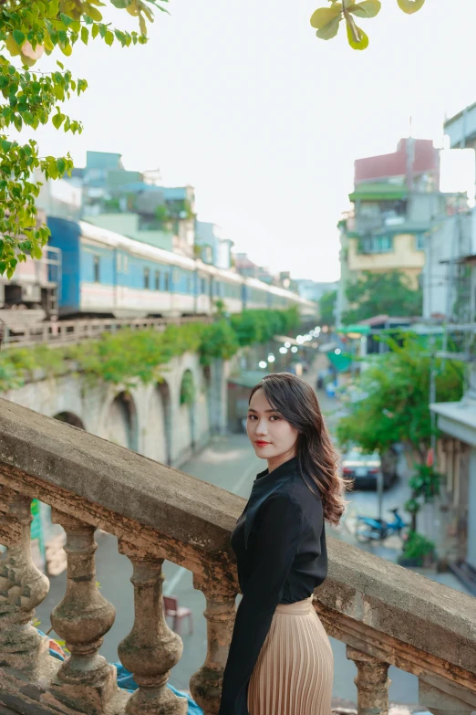 an attractive young lady is standing on a balcony railing