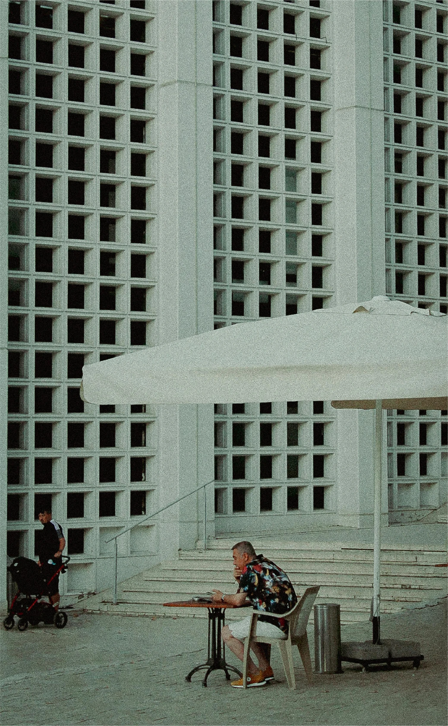 two men sitting under an umbrella on benches