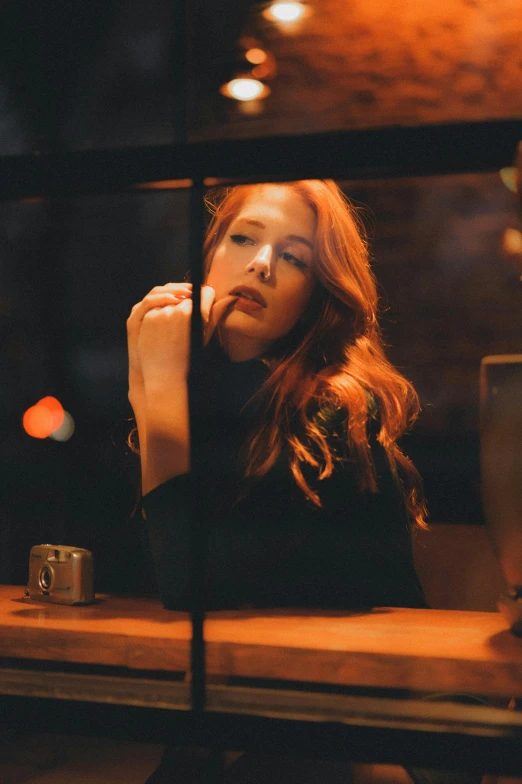 a beautiful woman sitting at a table in front of a window