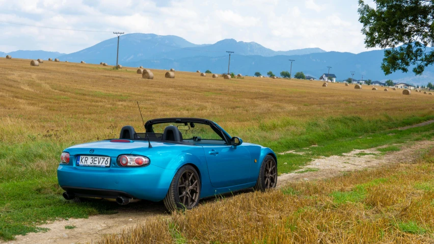 a blue sports car is parked on a rural trail