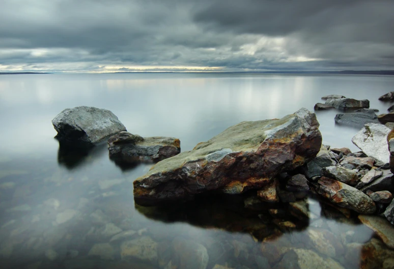 large rocks sit in the middle of a calm lake