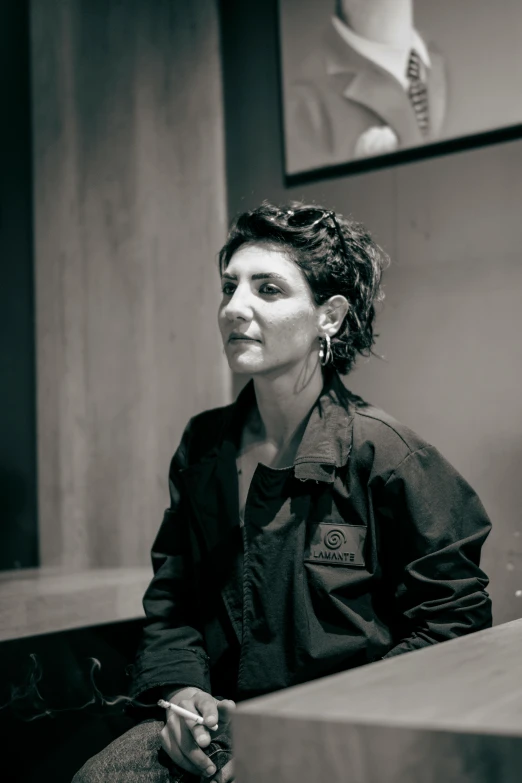 a woman wearing a black shirt and sitting in front of paintings