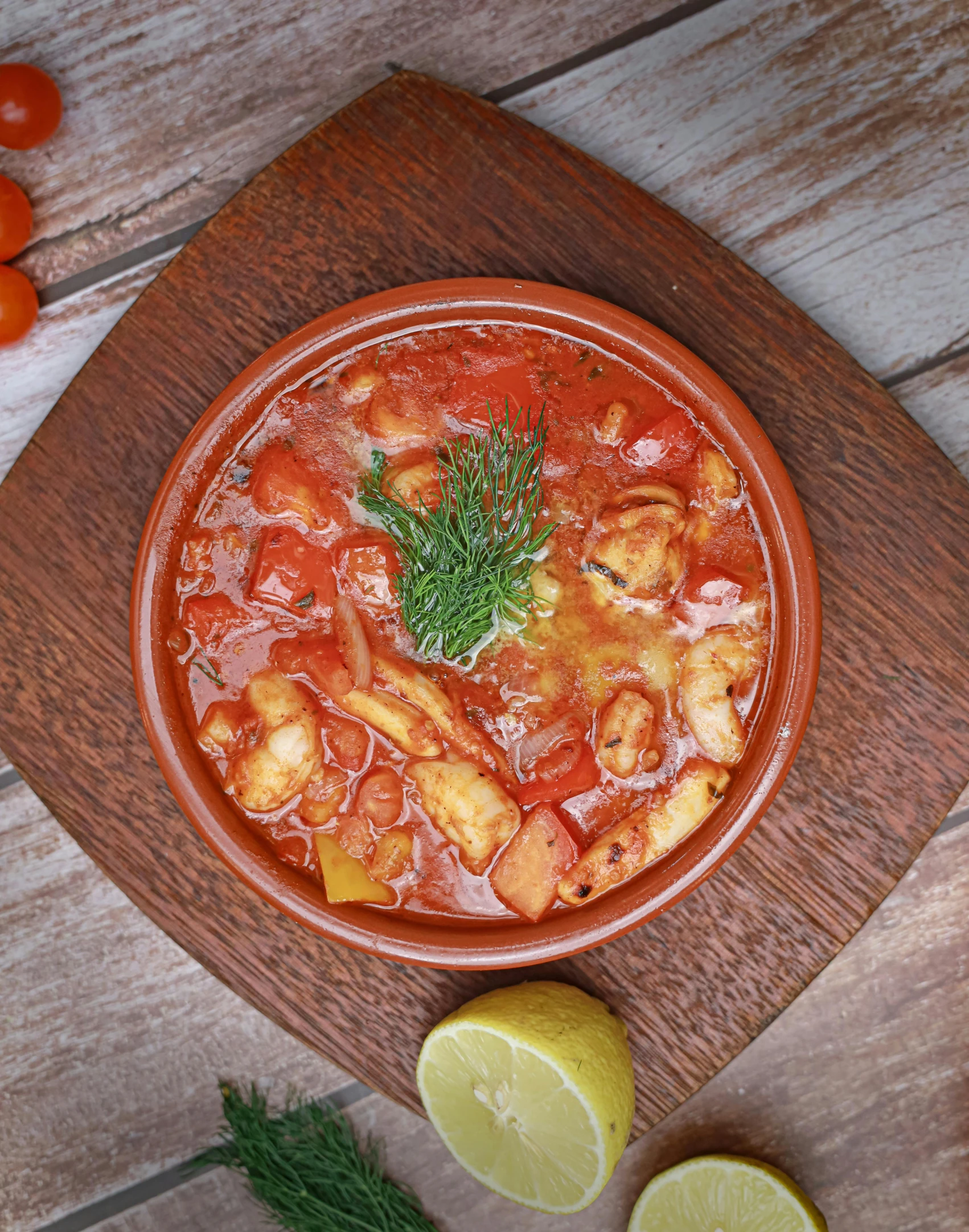 the bowl is filled with tomato soup on the wooden platter