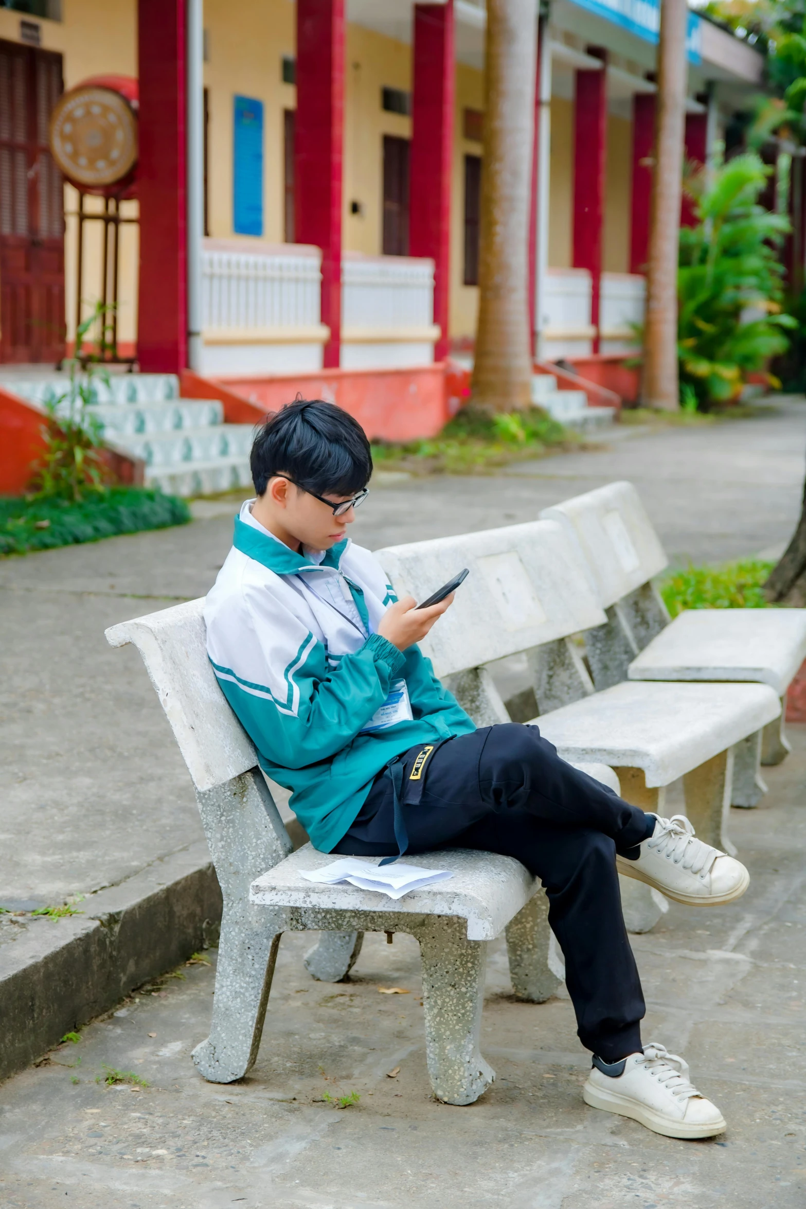 a young man sitting on top of a bench using a cell phone