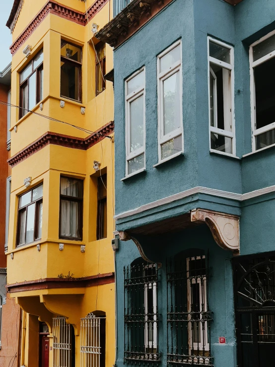 a two story blue and yellow building sitting in front of another orange one