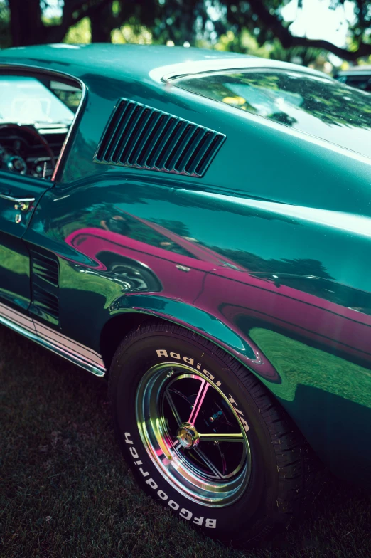 a green mustang with black wheels and chrome tires