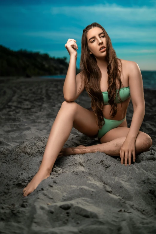 a woman in green sitting on the beach