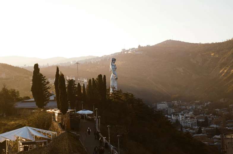 the statue is next to a tall hill