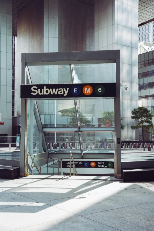 a subway entrance with signs and stairs leading to it