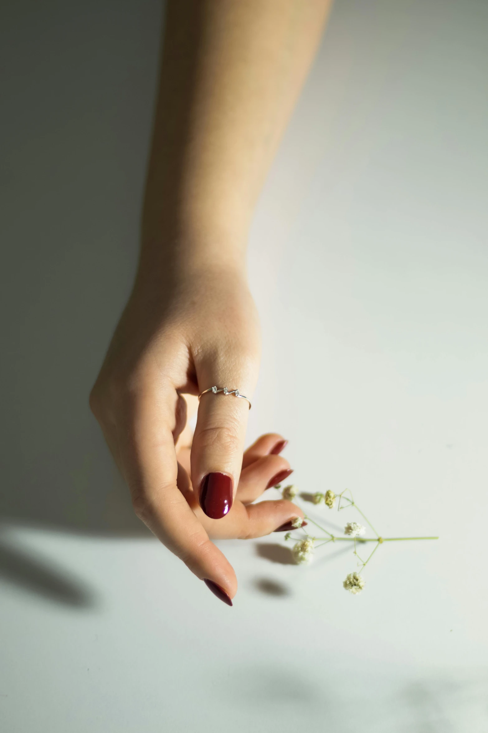 a woman's hand with red nail holding flowers