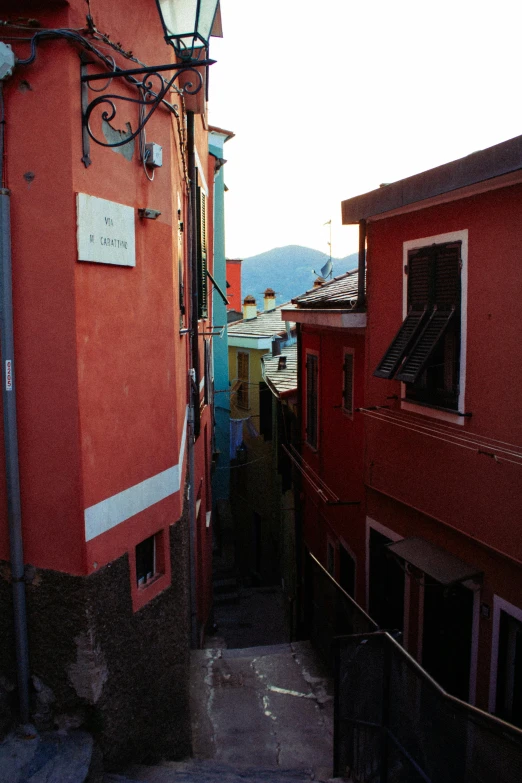 an alley way has orange buildings and red shutters