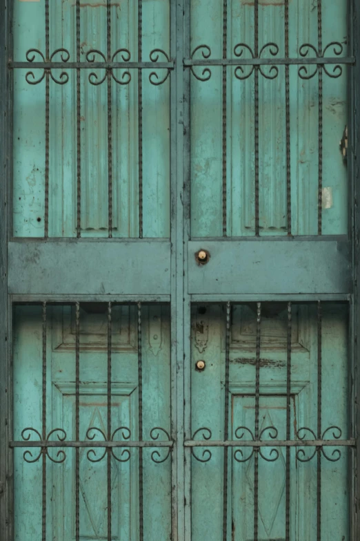 two metal doors are closed on a turquoise metal surface