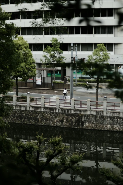 someone with an umbrella crosses a bridge in front of a large building