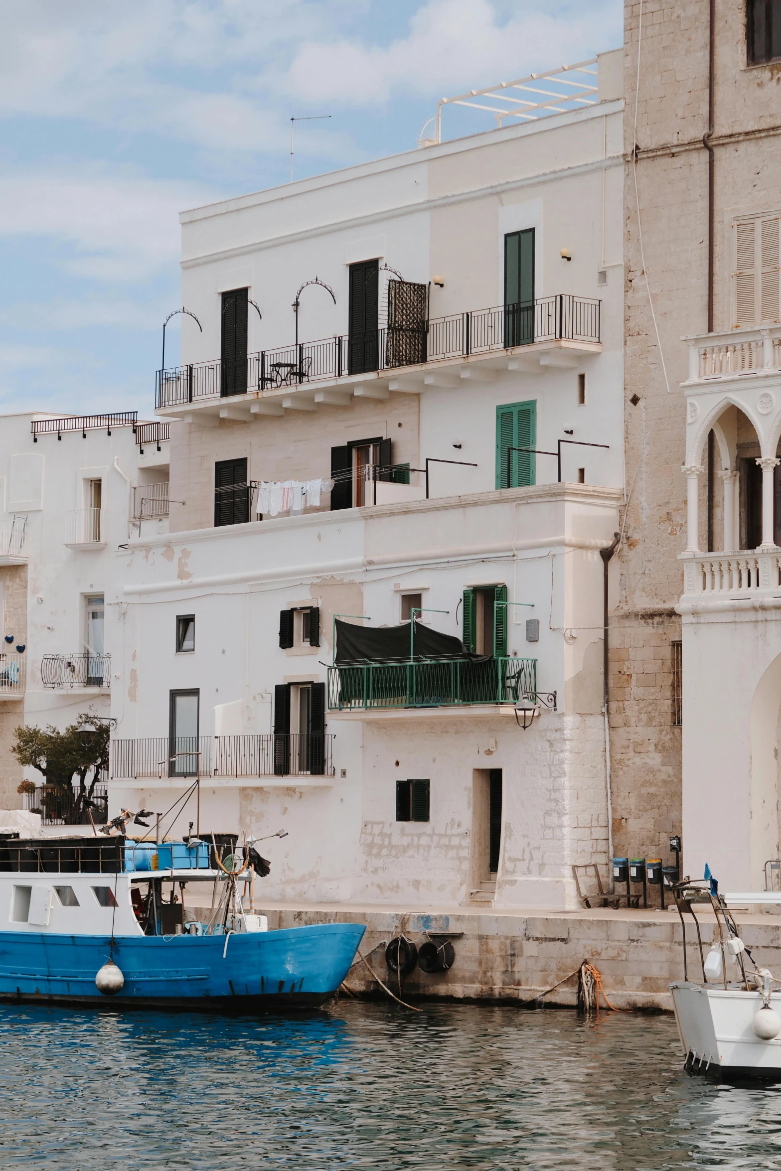 a white and blue boat in the ocean next to some buildings