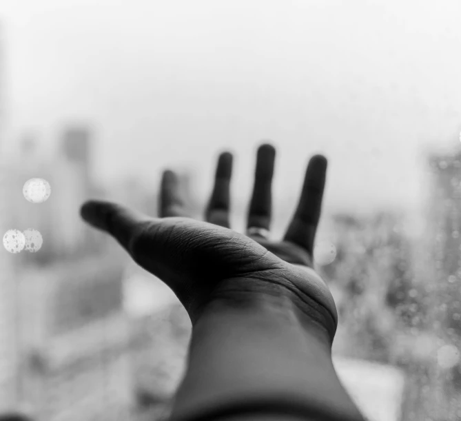 an open hand with black ink pointing up and buildings in the background