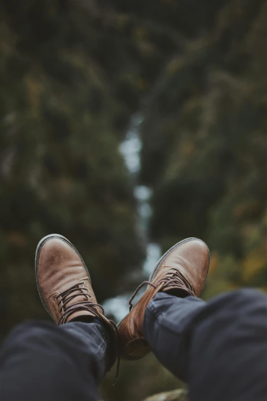 a person is wearing brown shoes in the woods