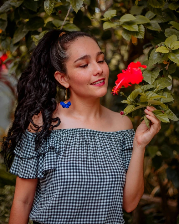 a woman wearing a black and white checkered top holding flowers