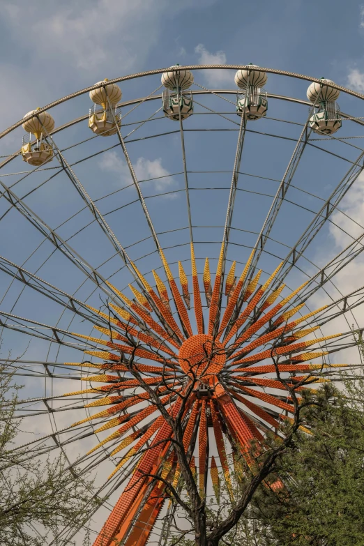 an orange ferris wheel with lights on and some trees in front of it