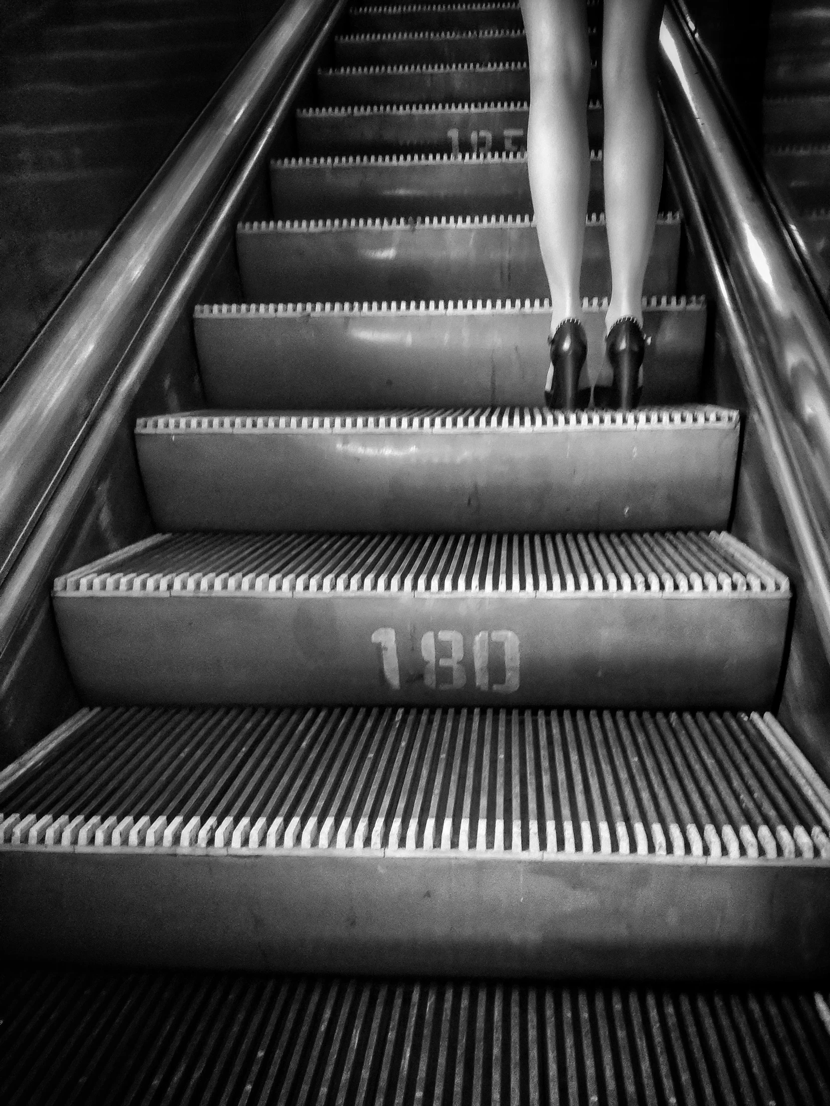 someone walking up an escalator near another set of stairs