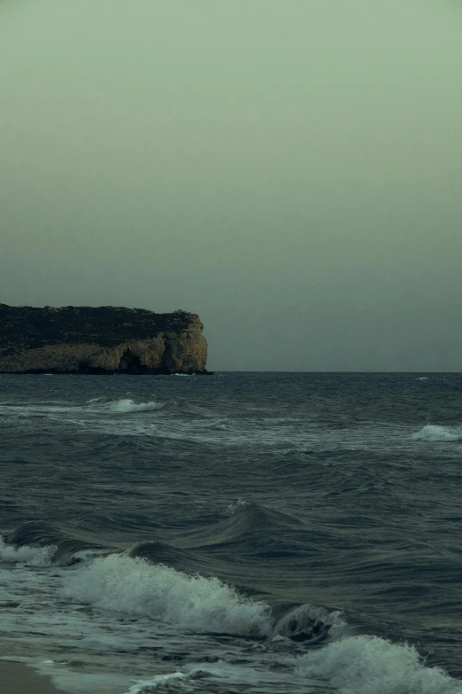 a lone boat traveling through the ocean under a foggy sky