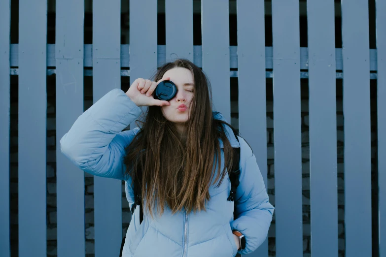 young woman taking po with camera lens and looking into camera