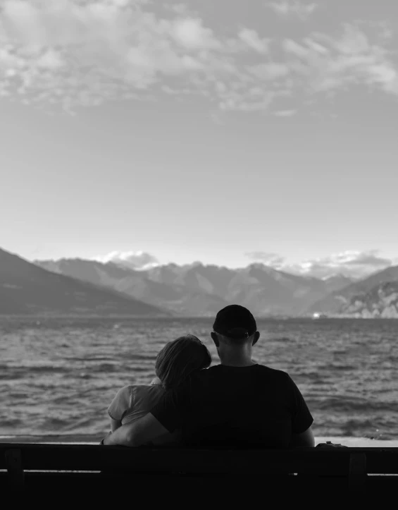 black and white po of people sitting on a bench looking at the water