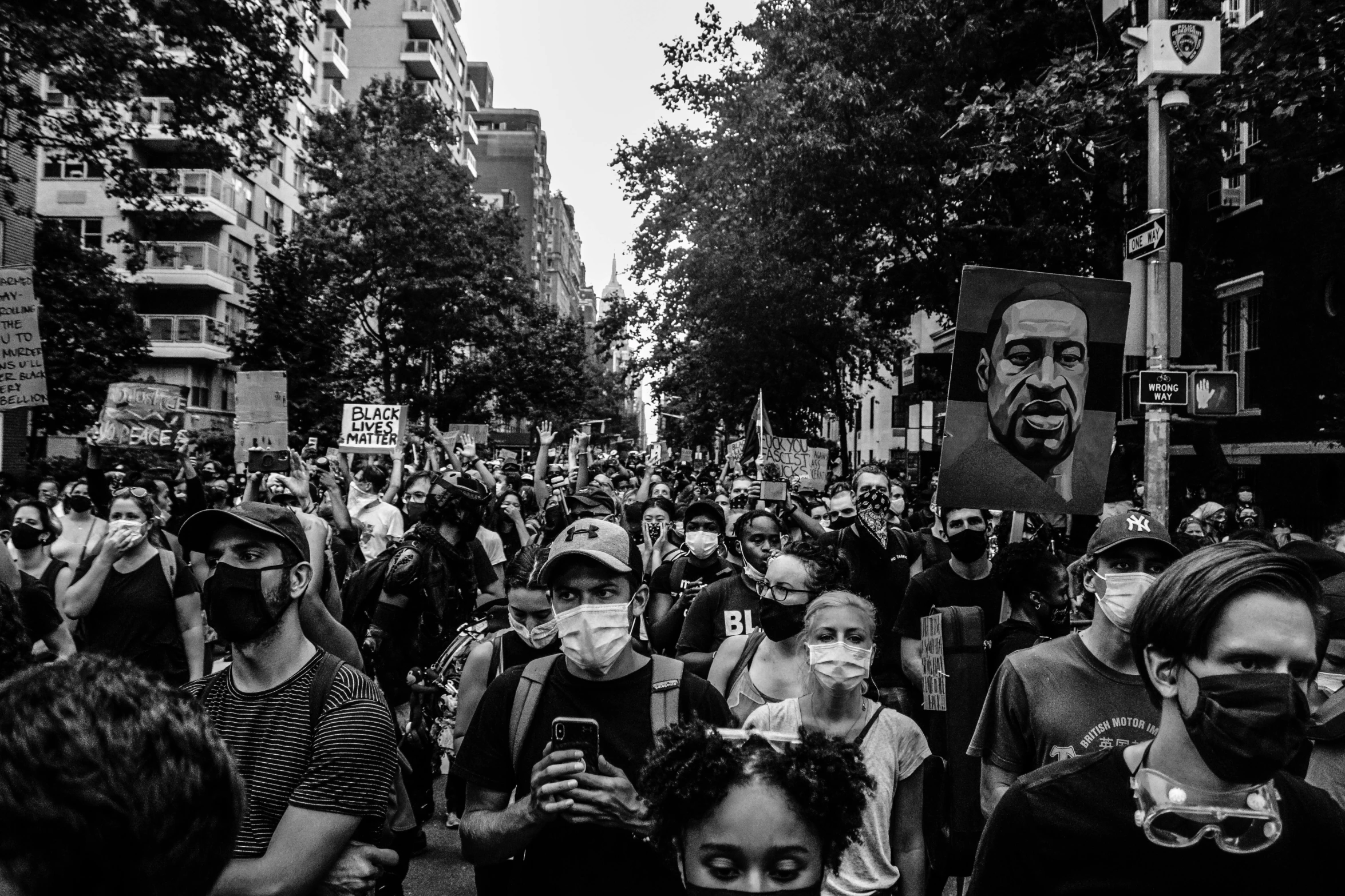 a crowd of people walking down a street holding cell phones