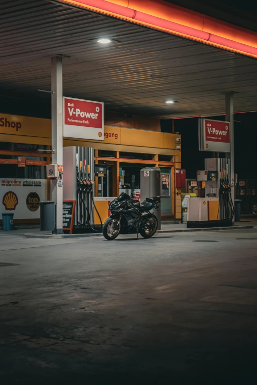 a motorcycle sitting in front of a fuel station