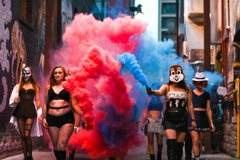 four woman wearing costumes with colorful smoke