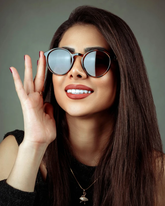 a woman wearing glasses and standing in front of a mirror