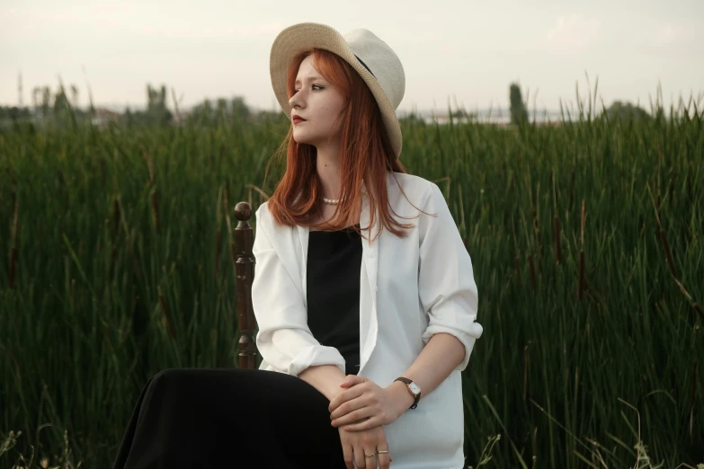 a woman wearing a hat is sitting on a bench