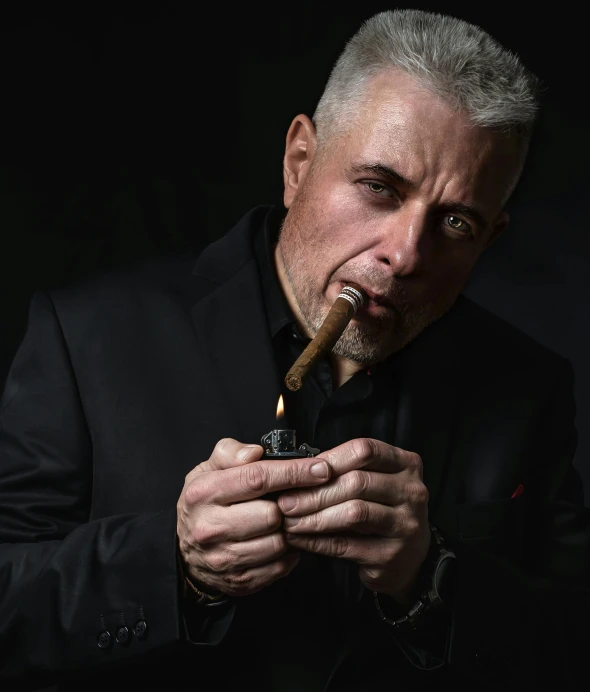 man with white hair holding up a cigar