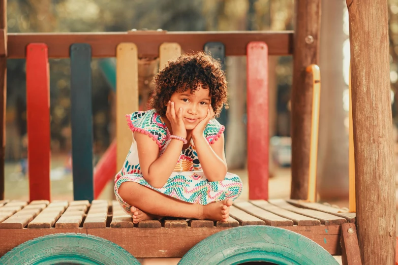 a young child sitting on top of a wooden bench