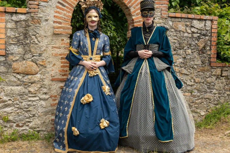 two people standing in elaborate clothing with one person wearing a crown