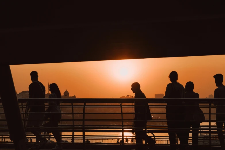 people standing next to a bridge watching the sun rise